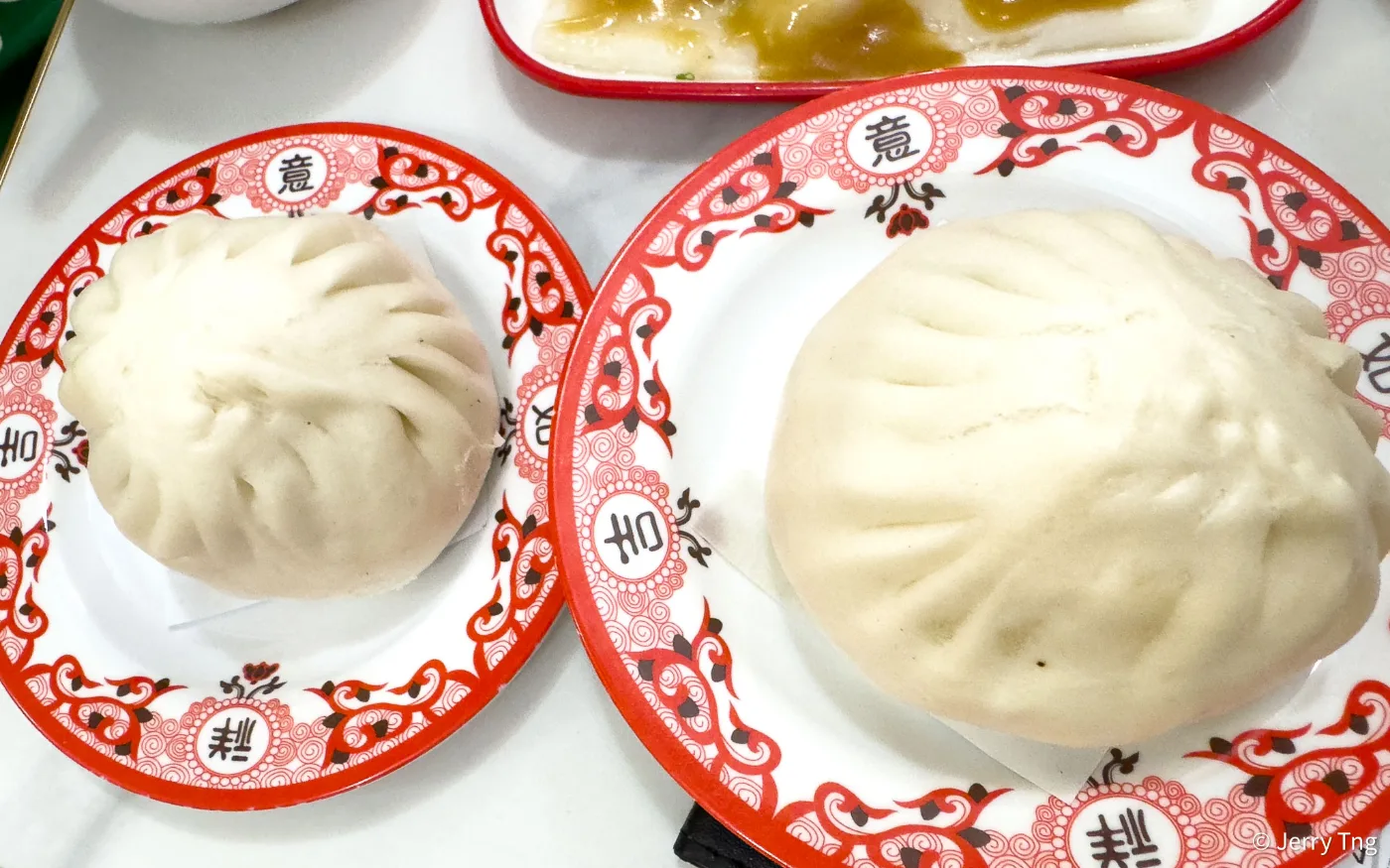 Two of 126 Dim Sum&rsquo;s big pao, one large and one small, on the shop&rsquo;s red-patterned house plates
