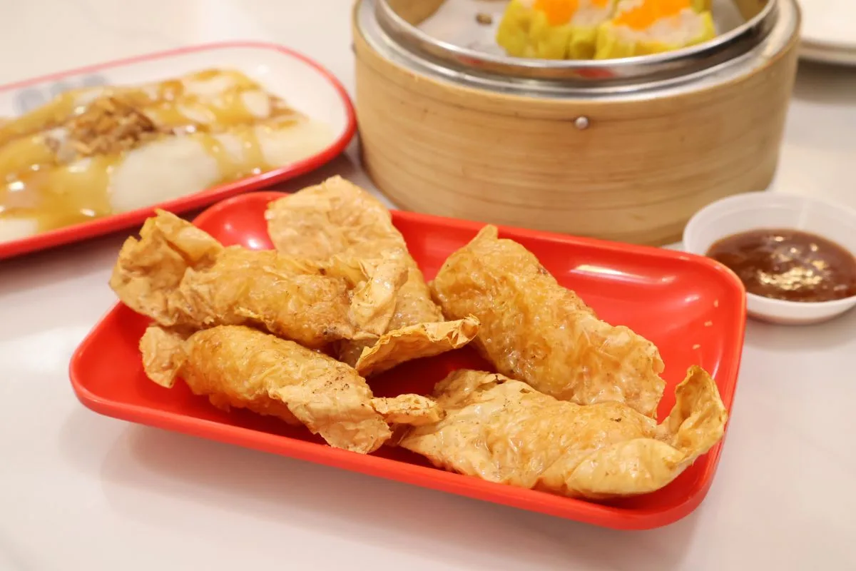 126 Dim Sum&rsquo;s crispy bean curd skin rolls on a red plate with a dipping sauce