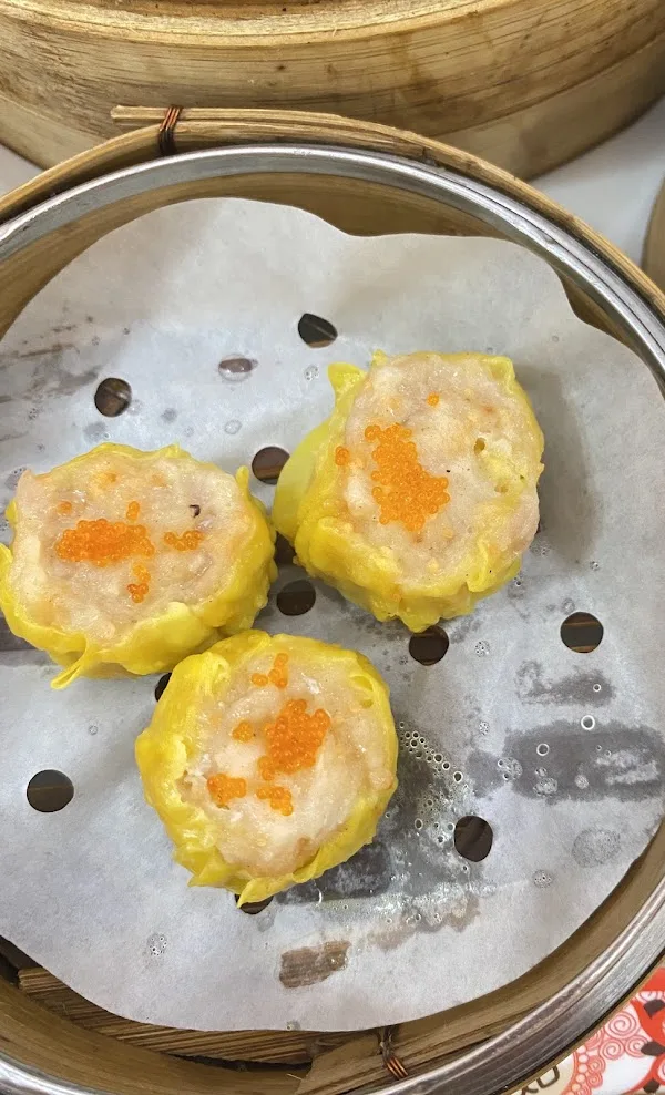 Three of 126 Dim Sum&rsquo;s ebiko siew mai topped with orange roe, in a bamboo steamer