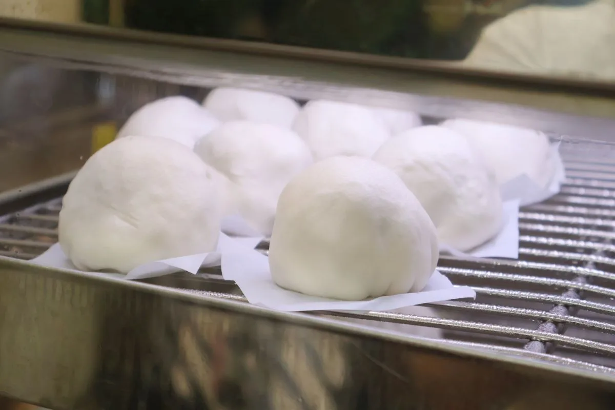 Rows of large white bao resting on the steaming rack in the 126 Dim Sum kitchen