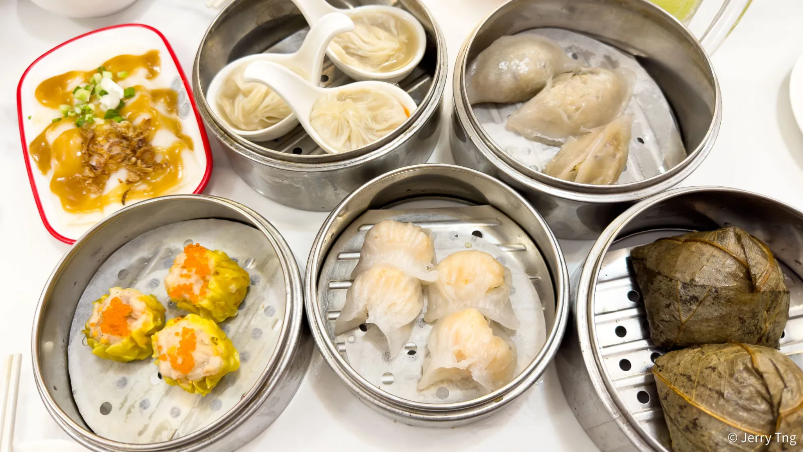 An overhead spread of 126 Dim Sum steamers &mdash; xiao long bao, har gow, siew mai, lotus rice and rice rolls across one table